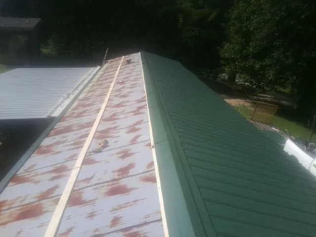Old rusted panels beside newly installed green metal roofing — Wind Damage Roof Repair by Roofing Brothers in Coram