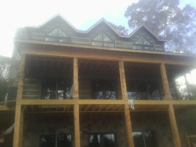Dormers and porch framing on a large log home under construction — Roof Coating work by our crew in Coram