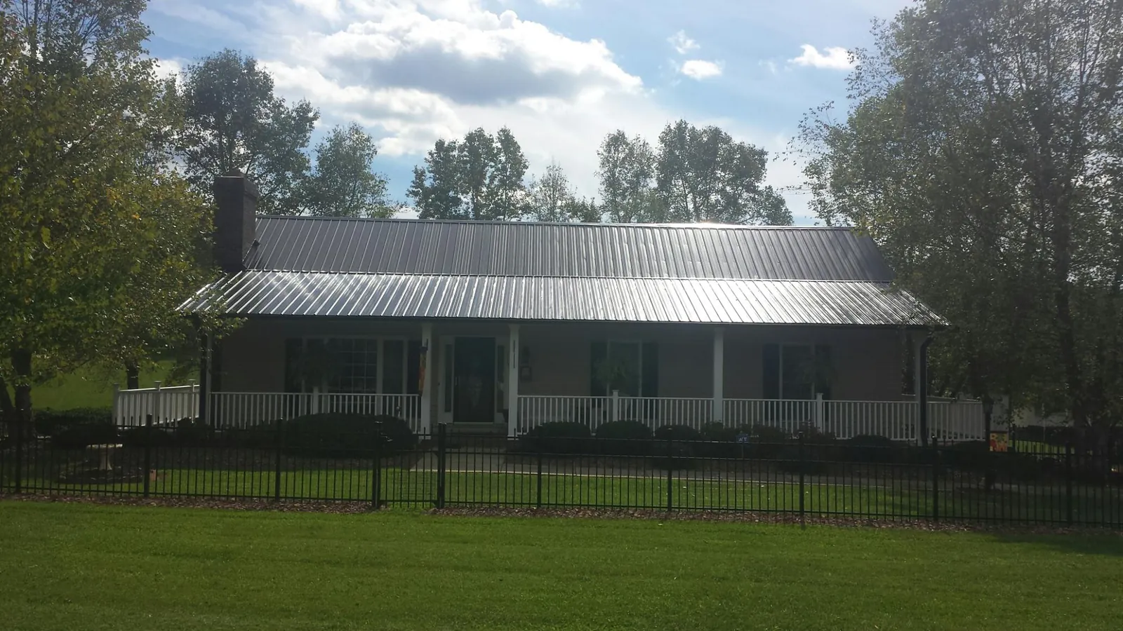Gray metal roof on a brick ranch with a full width front porch — Gutter Guard Installation work by our crew in Coram